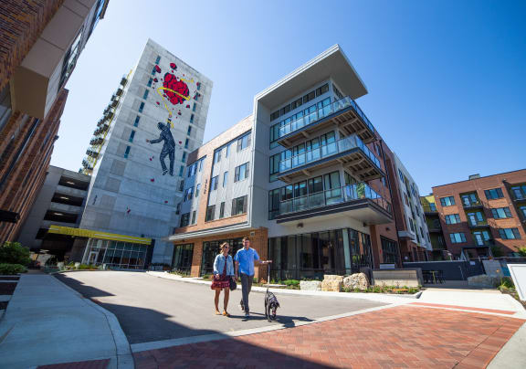 a man and a woman walking a dog in front of a building at CityWay Apartments, Indianapolis