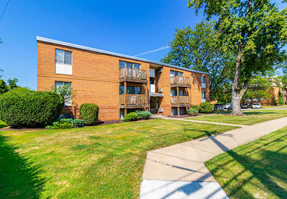 exterior view of a brick apartment building with grass and trees