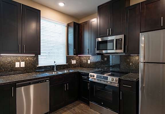 A kitchen with black cabinets and stainless steel appliances.