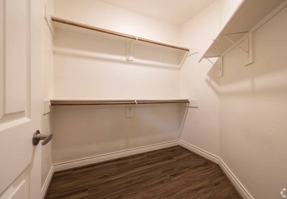 A white closet with a door and shelves.