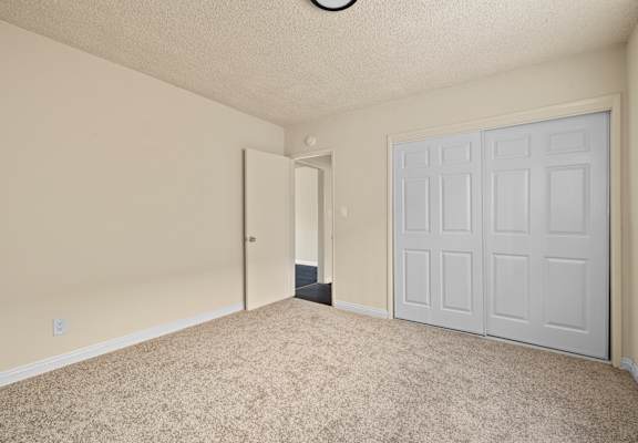 A room with a white door and carpeted floor.