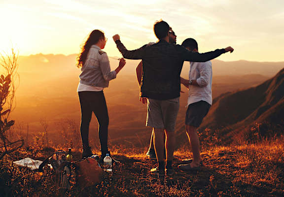 a group of people standing on a mountain at sunset