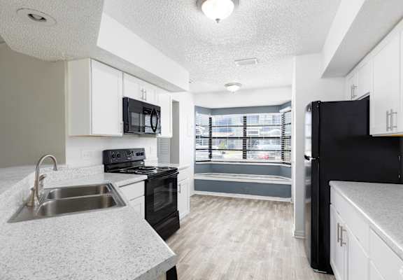 an empty kitchen with black appliances and white cabinets
