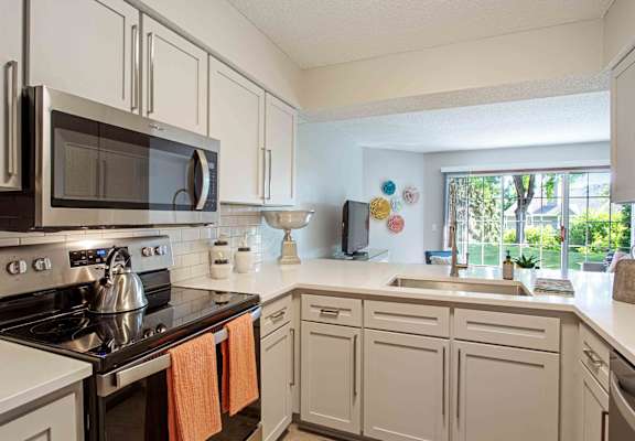 kitchen with stainless steel appliances and white cabinets and a window at Seasons Villas, Woodbury Minnesota