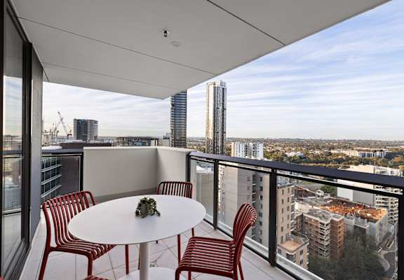A balcony with a table and chairs overlooking a cityscape.