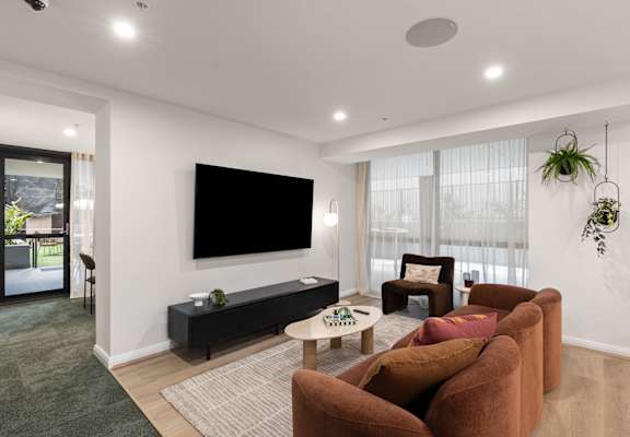A living room with a flat screen TV mounted on the wall.