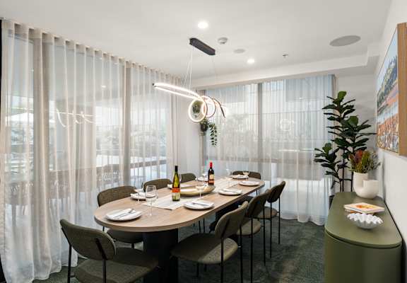 A dining room with a table set for two with a bottle of wine and a plate of food.