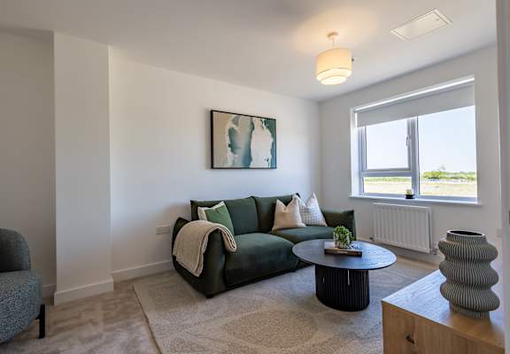 A living room with a green couch, a grey armchair, a coffee table, and a painting on the wall.