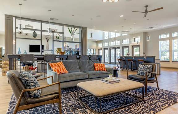 A residential lounge area with a grey couch, a brown chair, and a rug at Parkstone at Knightdale apartments in Knightdale, NC.