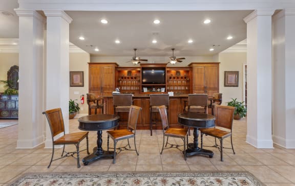 a living room with a table and a bar with chairs at Bedford Parke Apartments in Georgia 31088