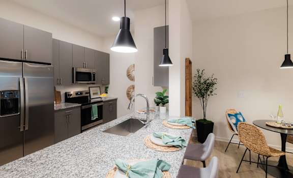 A modern kitchen with a dining table set for two.