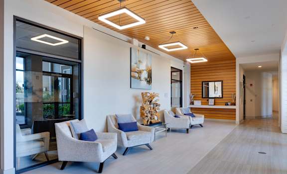 A modern waiting room with grey chairs and a wooden ceiling.