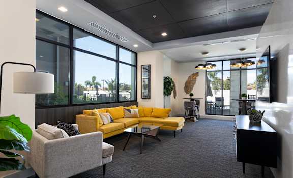 A living room with a yellow couch and a grey armchair.
