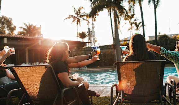 a group of people sitting around a swimming pool with drinks