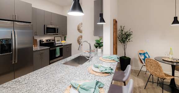 A modern kitchen with a dining table set for two.