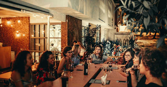 A group of people are sitting around a table in a dimly lit restaurant.
