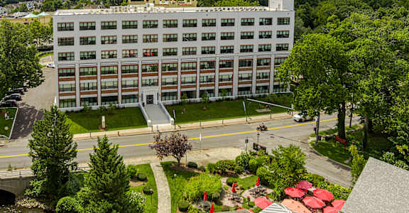 A large white building with a lot of windows is surrounded by trees.