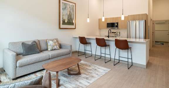 A living room with a grey couch, a wooden coffee table, and a painting on the wall.