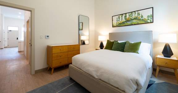 A bedroom with a bed, nightstand, and lamp.