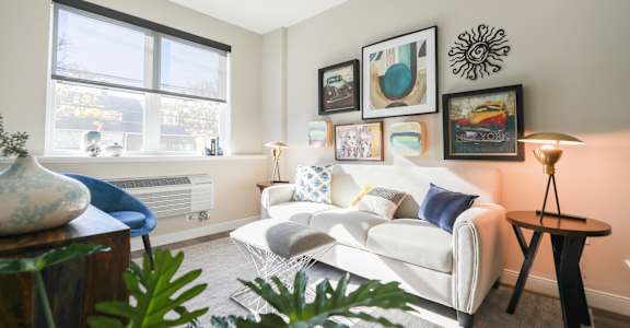 A living room with a white couch, a blue chair, and a table with a vase on it at Walnut View Apartments, Allentown, PA, 18102