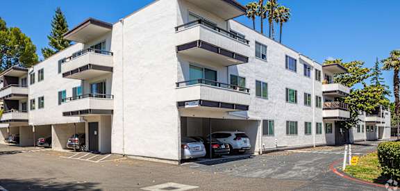 a white apartment building with cars parked in front of it