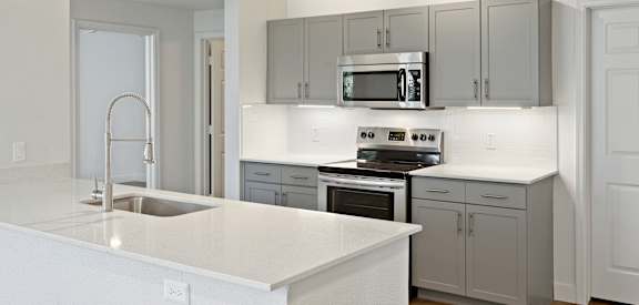 A modern kitchen with a white countertop and stainless steel appliances.