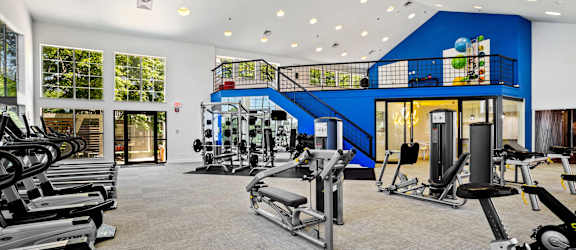a spacious fitness center with cardio equipment and a spiral staircase