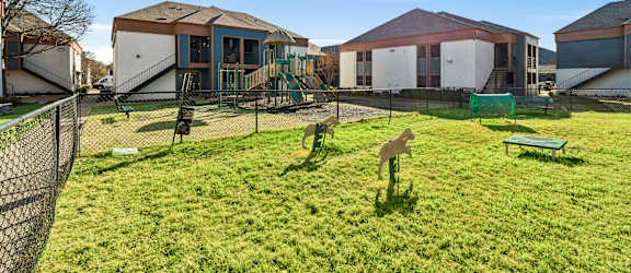A green lawn in front of a building with a fence.