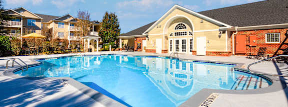 A large outdoor swimming pool with a slide and a building in the background.