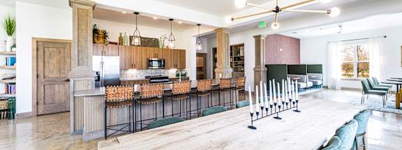 a long communal table in a large kitchen with a bar and a living room at The Parker Austin, Pflugerville, 78660