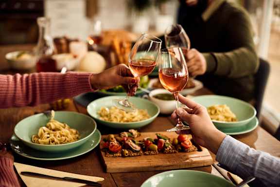 A group of people toasting with wine glasses in front of a meal. at Pinnex, Indiana, 46203
