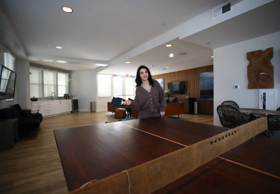 a woman standing in a living room with a ping pong table