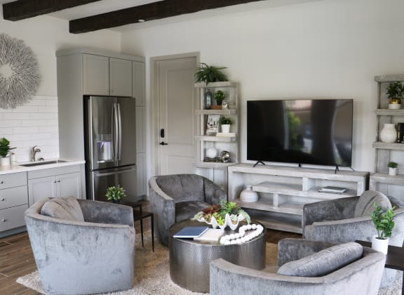 a living room with a tv on the wall and a kitchen in the background