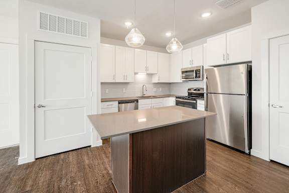 A modern kitchen with a center island and stainless steel appliances.