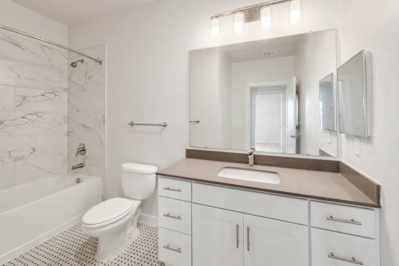 A white bathroom with a marble tile shower.