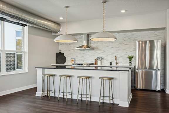 A kitchen with a white counter and stools.