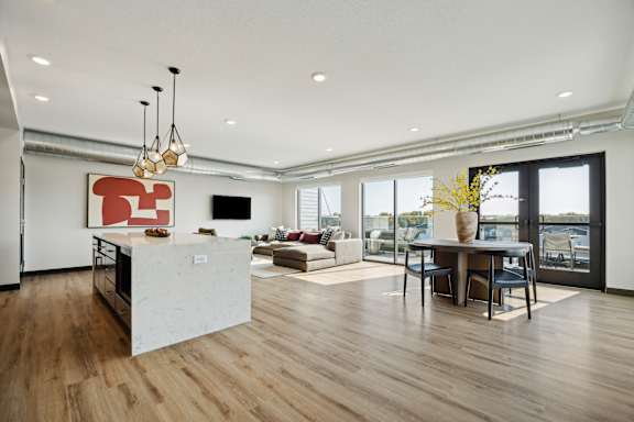 A modern kitchen with a white island and wooden floors.
