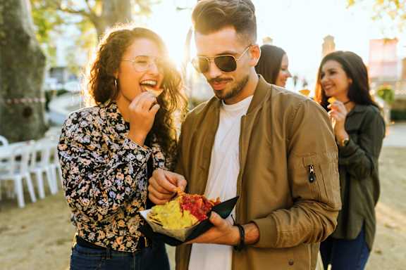 A man and a woman are sharing a meal outdoors.