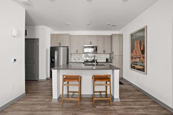 A kitchen with a bar stool and a fridge.