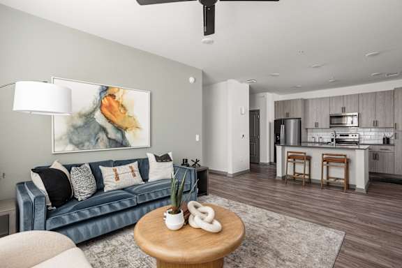 A living room with a blue couch and a painting on the wall.