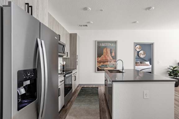 A modern kitchen with a refrigerator, sink, and cabinets.