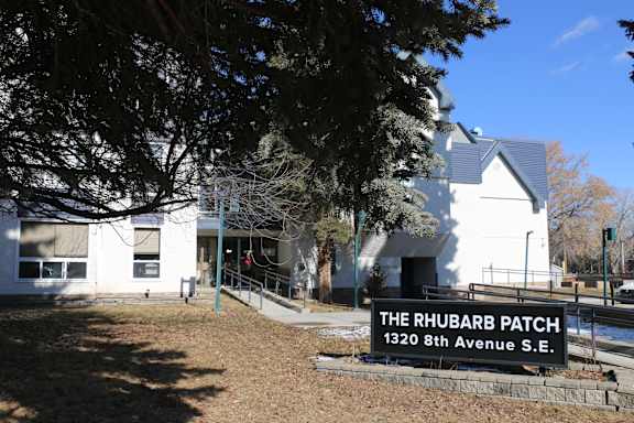 A white building with a sign that says "The Rhubarb Patch" in front of it.