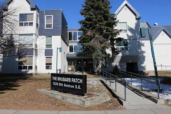 A sign in front of a building that says "The Rhubarb Patch 1320 8th Avenue S.E."