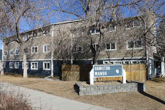 A sign that says Hamilton Manor is in front of a building.