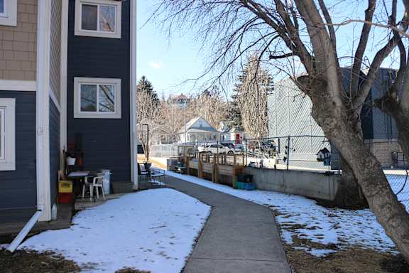A snow-covered sidewalk leads to a house.