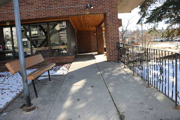 A brick building with a black iron fence and a bench.