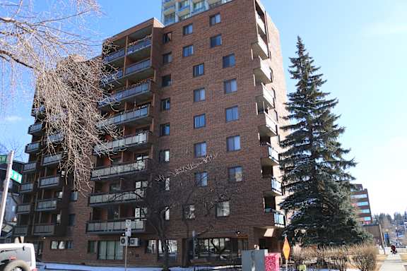 A tall brick building with balconies on the second floor.