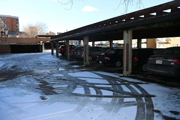A parking garage with cars parked and snow on the ground.