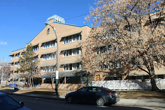A car is parked on the side of a street in front of a building.