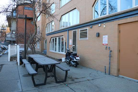 A picnic table is in front of a brick building.